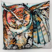 An owl pillow with a LARGE JOURNAL - HE REIGNS painting on it.