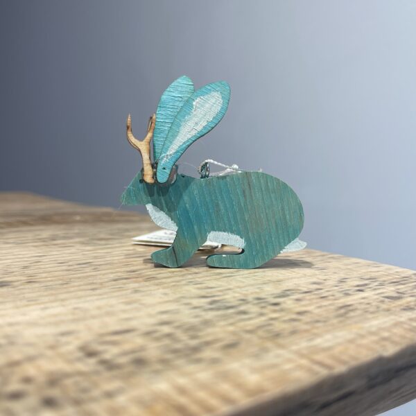 A JACKALOPE ORNAMENT - 2022 with horns on top of a wooden table.