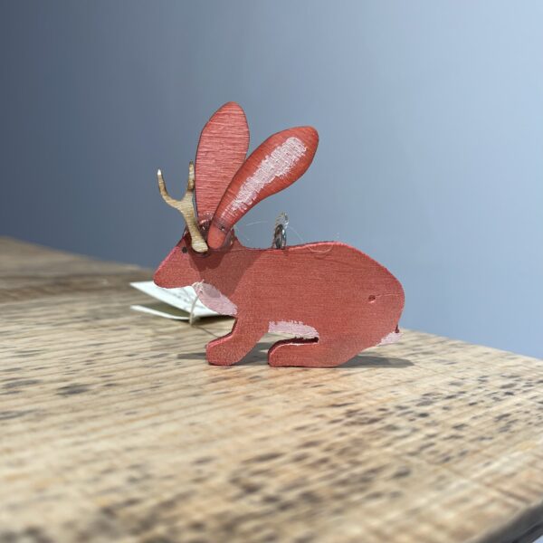A Jackalope Ornament - 2022 sitting on top of a wooden table.