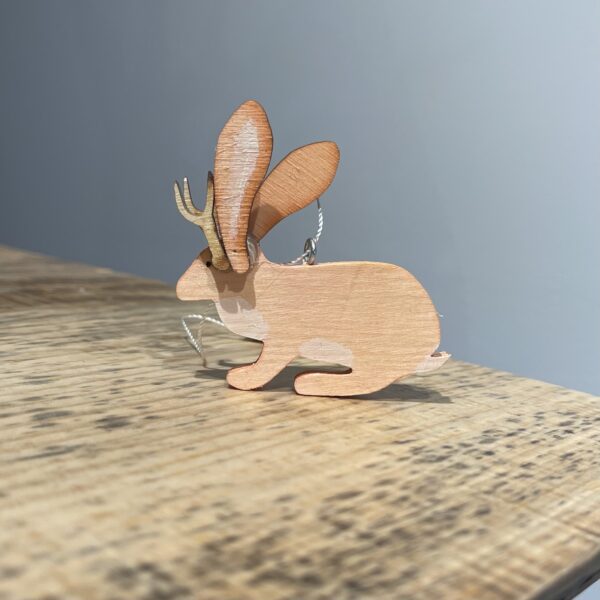 A JACKALOPE ORNAMENT - 2022 with antlers on top of a wooden table.