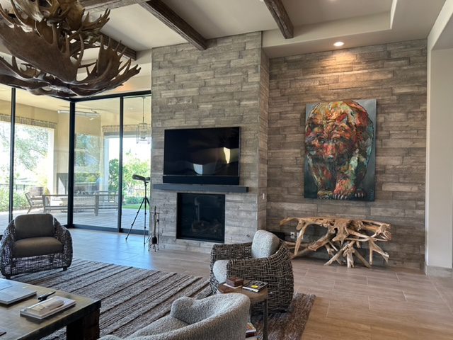 A living room with a stone fireplace and deer antlers.