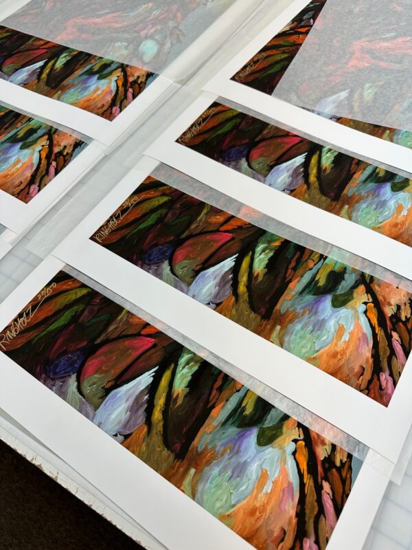 A stack of "Song On The Wind" Limited Edition Prints on a table.