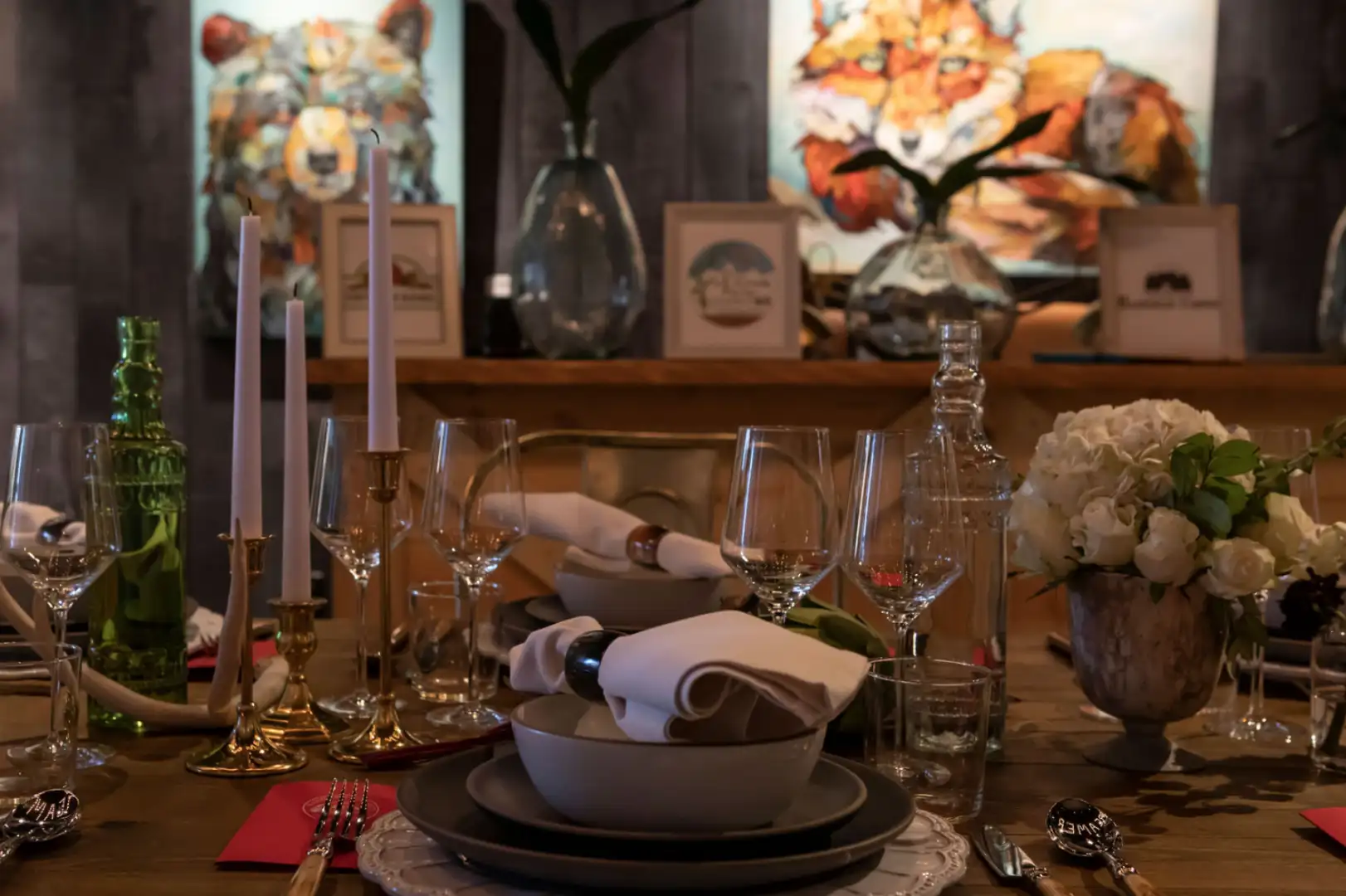 Elegant dining table set for a formal meal with artistic decor in the background.