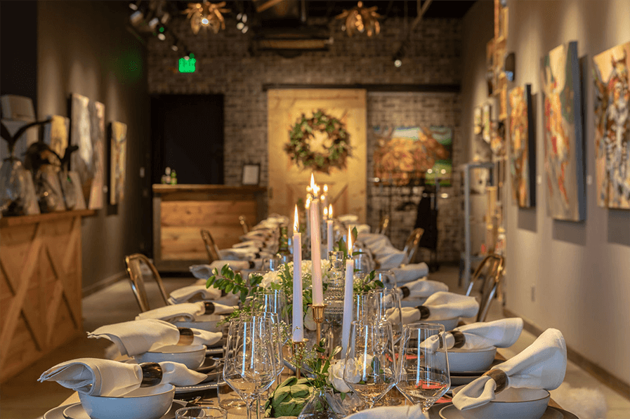 A table is set up in a room with paintings on the wall.