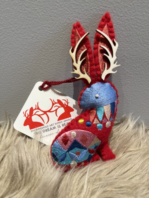 A red felt 2023 JACKALOPE ORNAMENT with antlers on it.